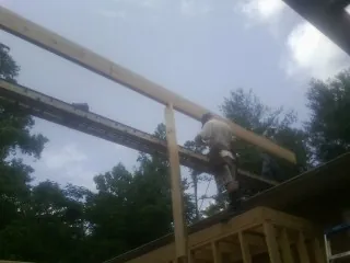Carpenter setting a ridge beam over a new addition frame — Ice Dam Removal by Roofing Brothers in Pine Ridge