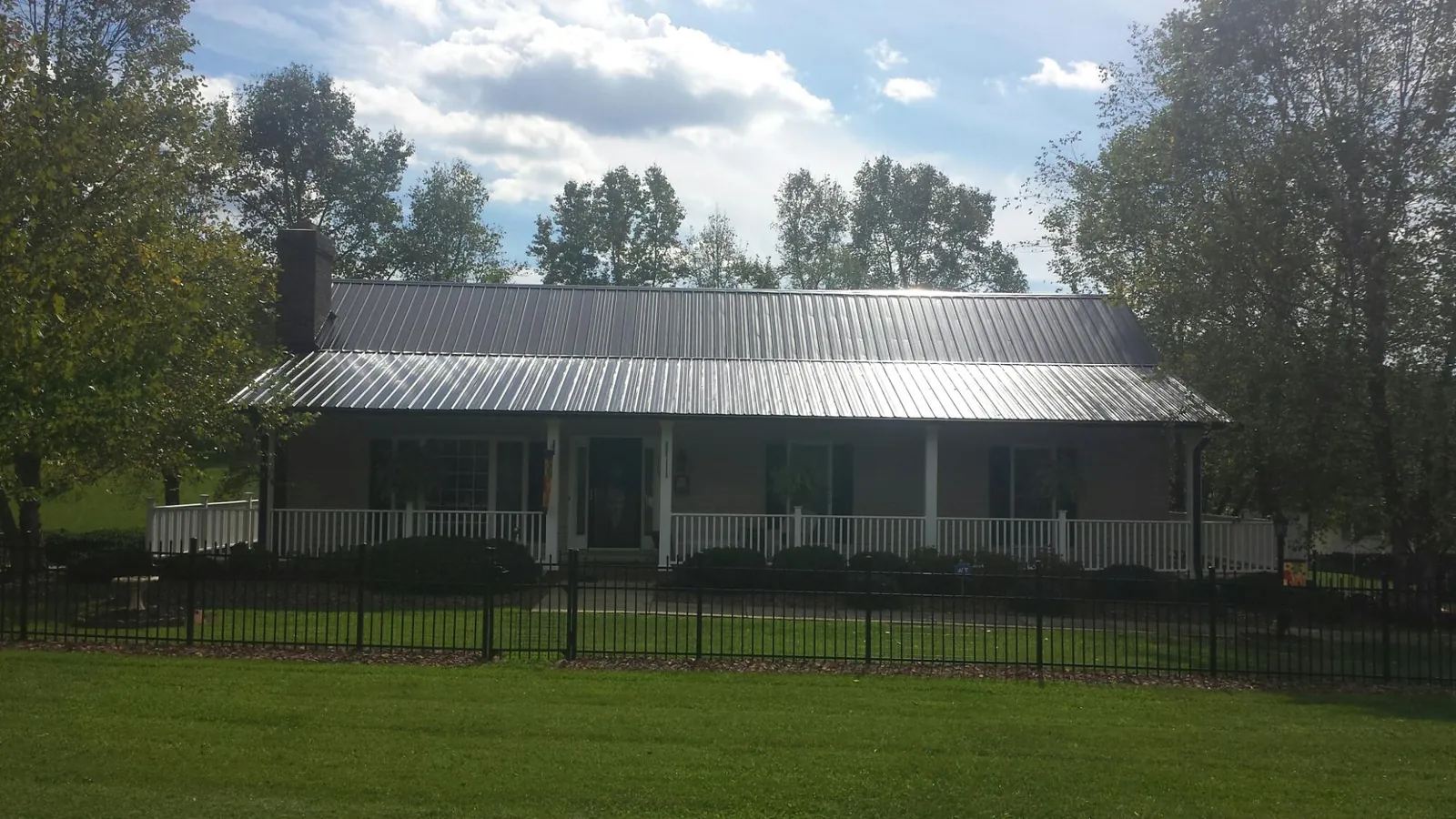 Gray metal roof on a brick ranch with a full width front porch — Gutter Guard Installation work by our crew in Pine Ridge