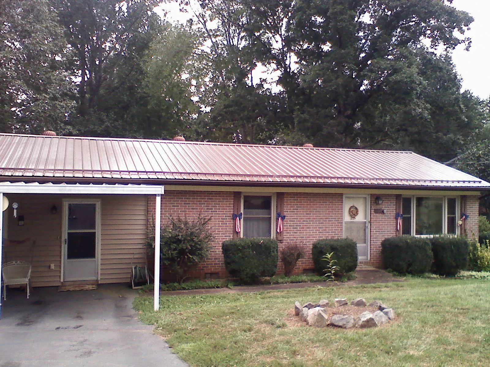 Bronze metal roof and carport on a brick ranch home — Roof Repair work by our crew in Pine Ridge