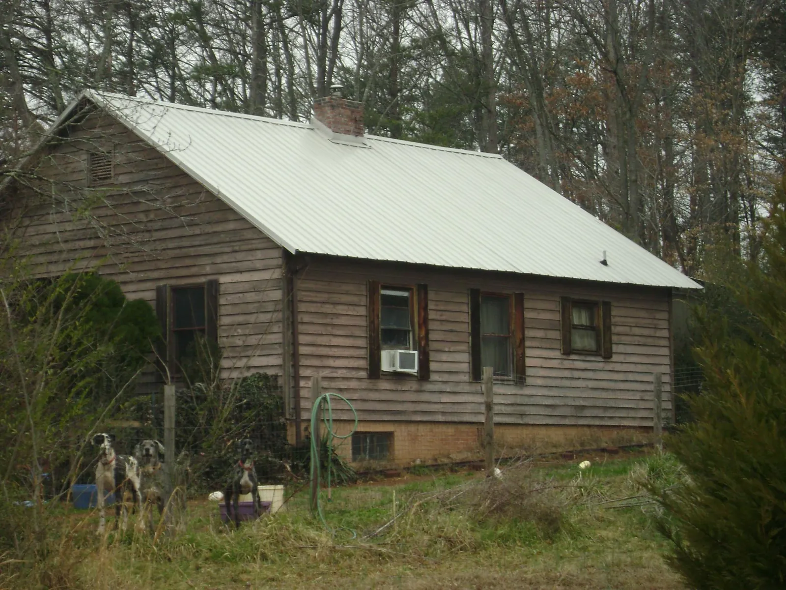 White metal roof on an old wood sided farmhouse, from a Metal Roof Installation job in Pine Ridge