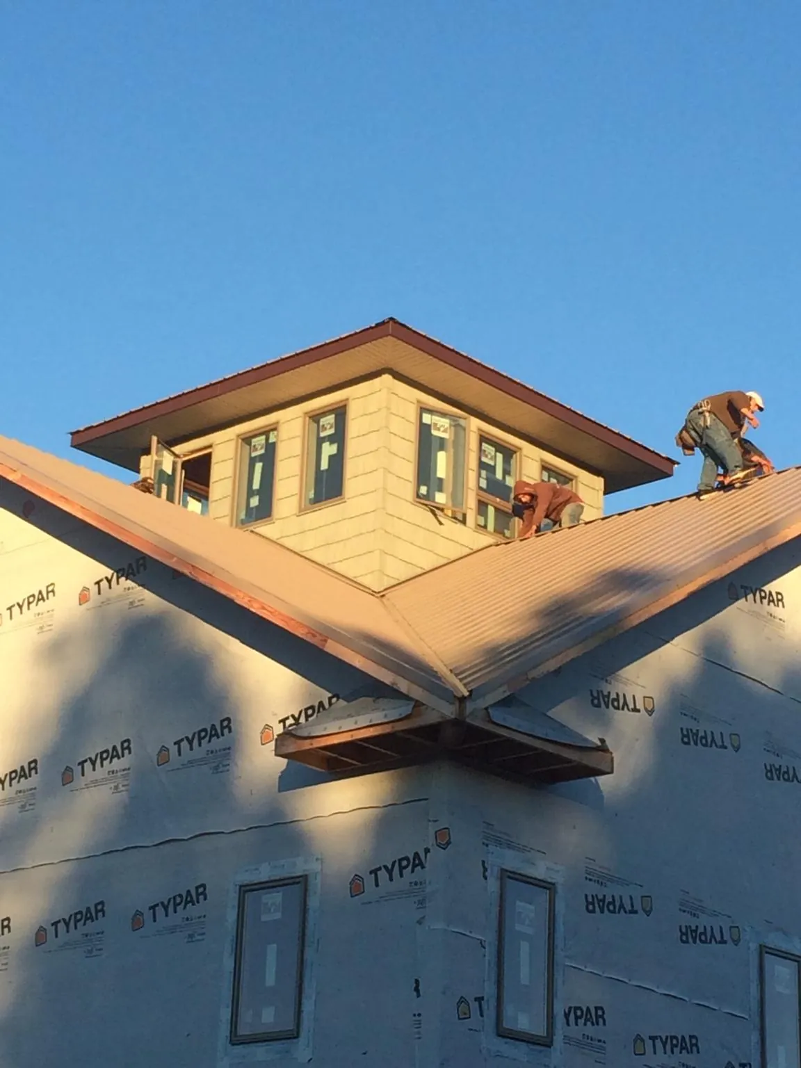 Roofers working around a rooftop cupola on a new metal roof at sunset — Roof Waterproofing in Pine Ridge by Roofing Brothers